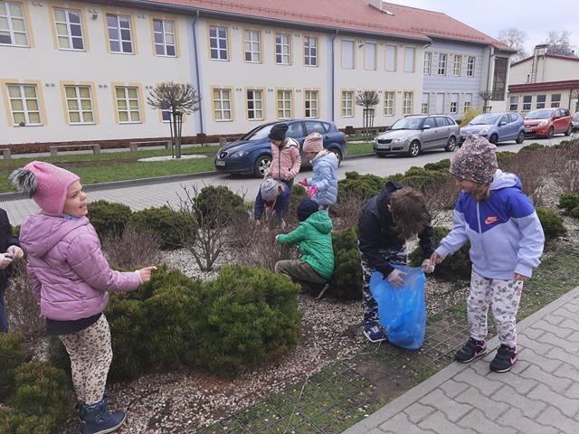dzieci sprzątają teren wokół szkoły